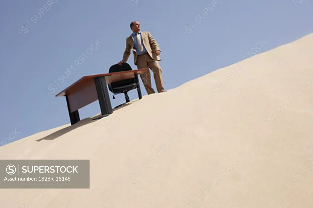 Businessman by Desk on Sand Dune   