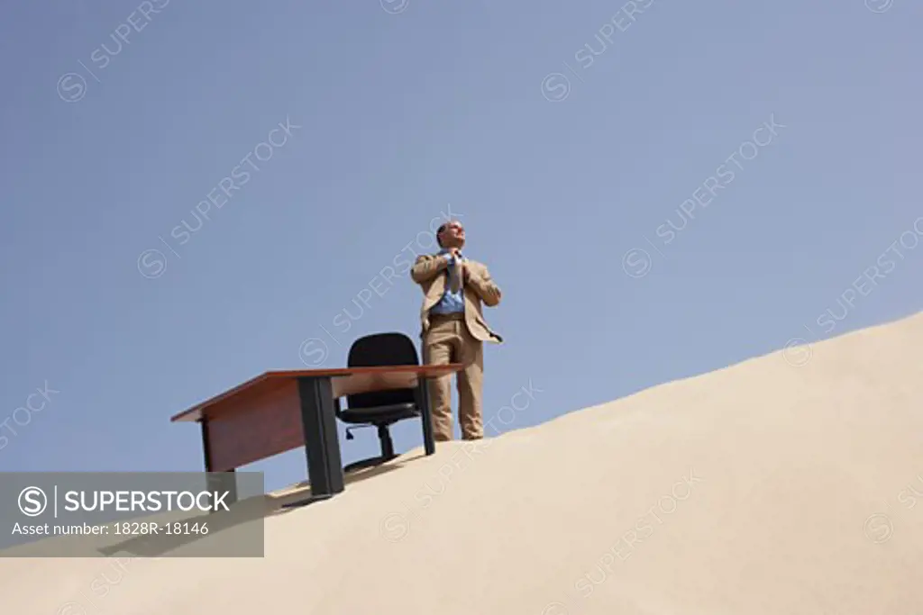Businessman by Desk on Sand Dune   