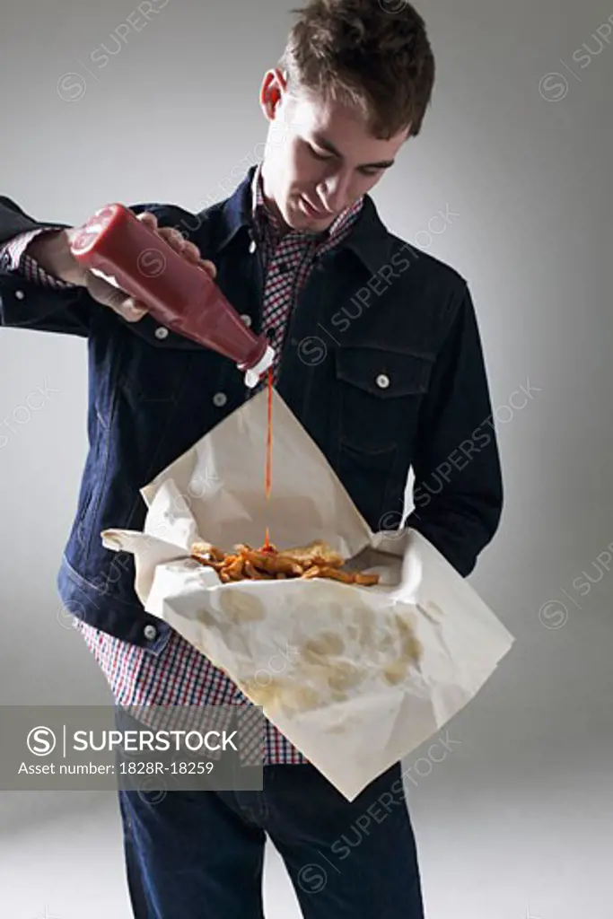 Man Pouring Ketchup on Fish and Chips   