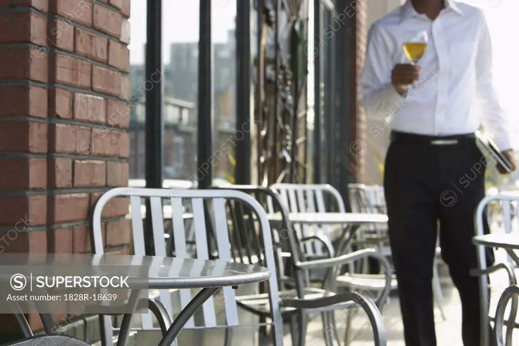 Waiter Carrying Glass of Wine on Restaurant Patio   