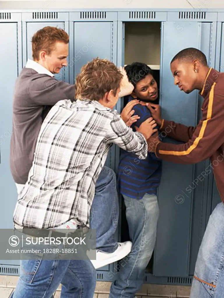 Group of Teens Stuffing Boy in Locker   