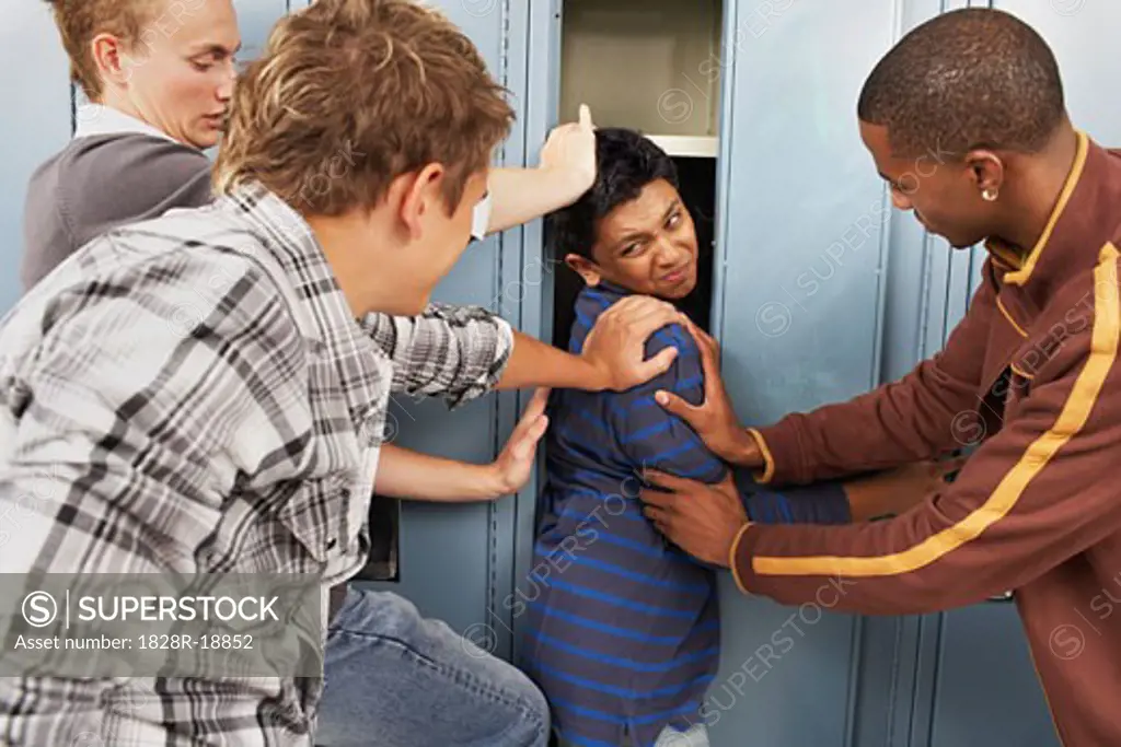Group of Teens Stuffing Boy in Locker   