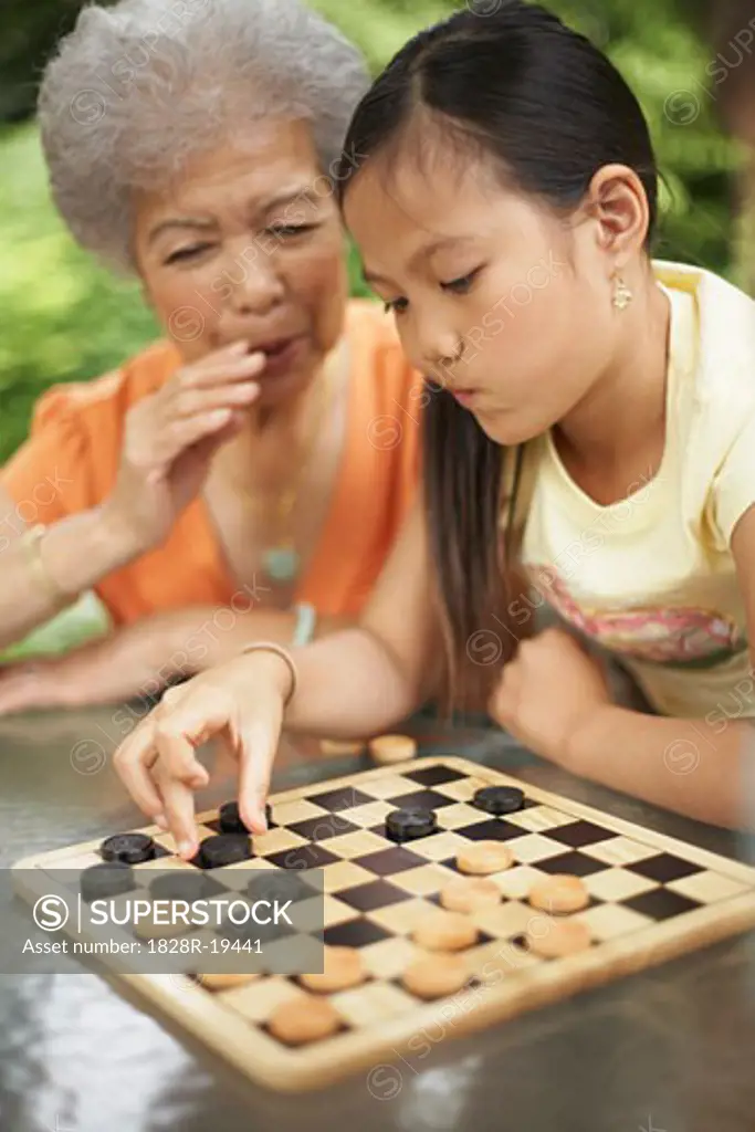 Grandmother Helping Granddaughter Play Checkers   