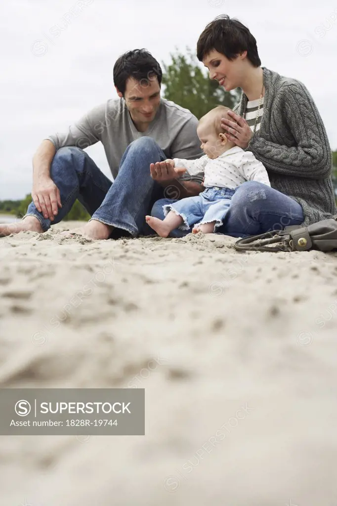 Family with Baby Sitting on Beach   