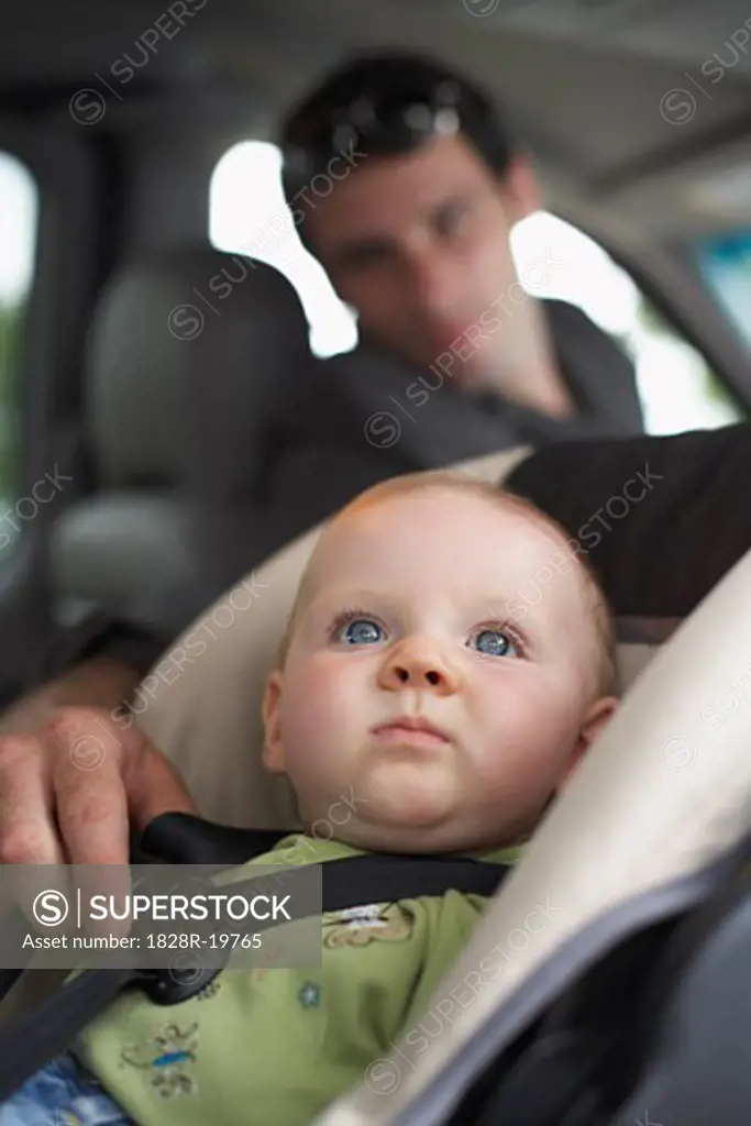 Father Adjusting Straps of Baby's Car Seat   