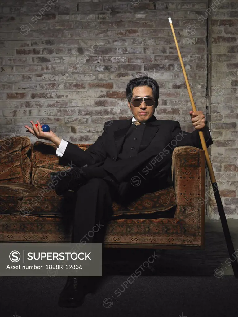 Portrait of Man on Sofa with Pool Cue and Billiard Balls   