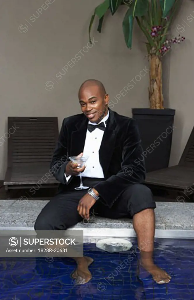 Man in Tuxedo with Feet in Pool Drinking Cocktail   