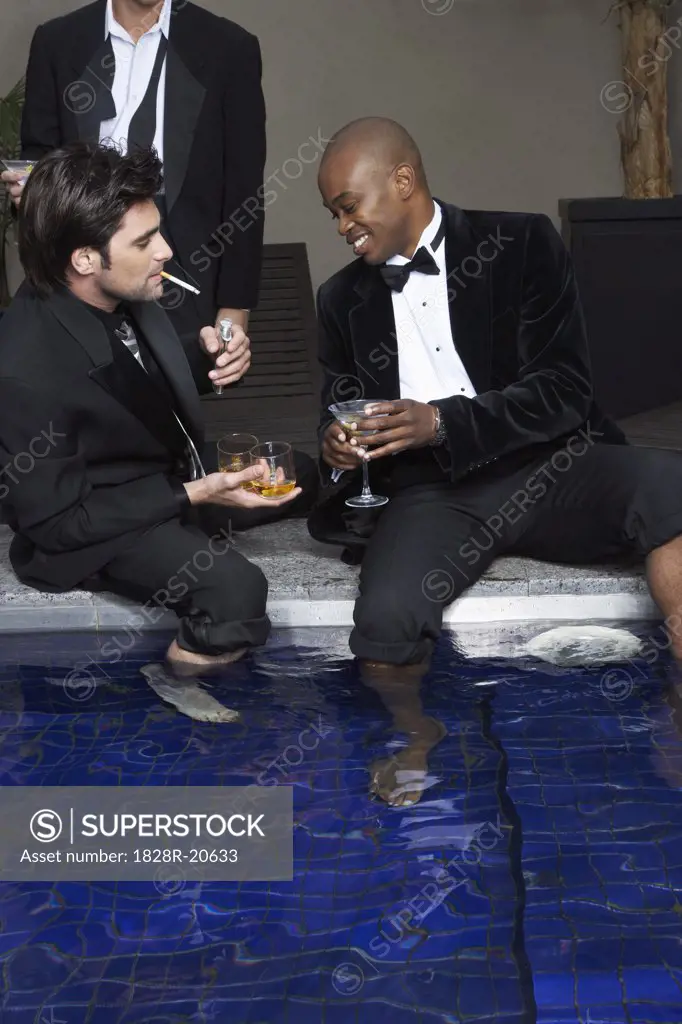 Men in Tuxedos with Feet in Pool Drinking Cocktails   