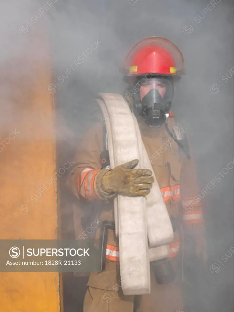 Firefighter Carrying Hose out of Smoky Building   