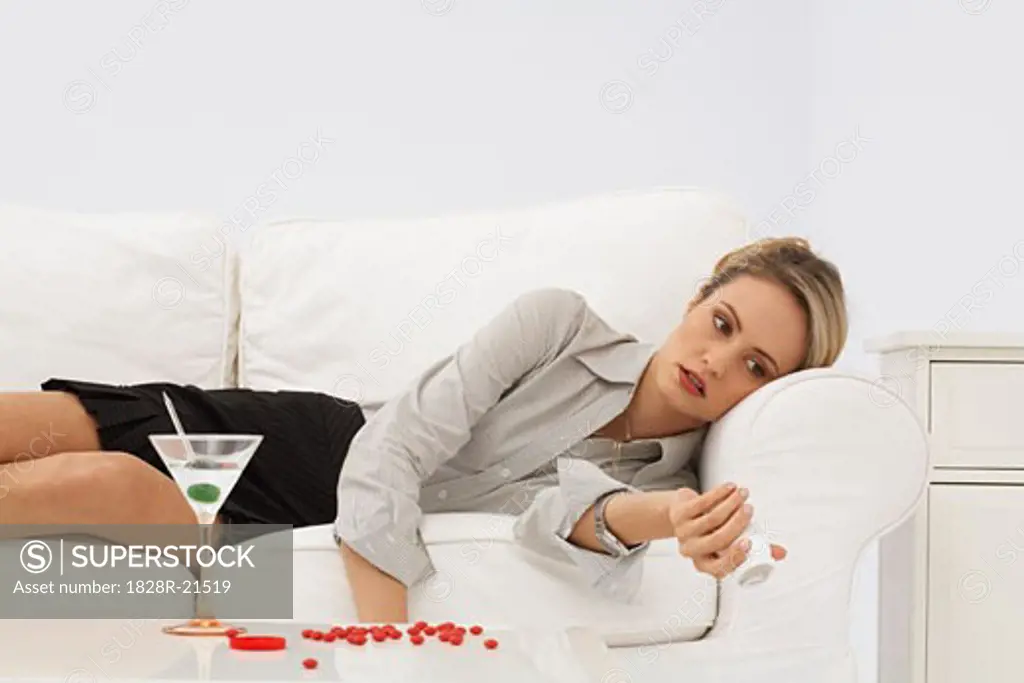 Businesswoman Lying on Sofa, with Pills and Martini   
