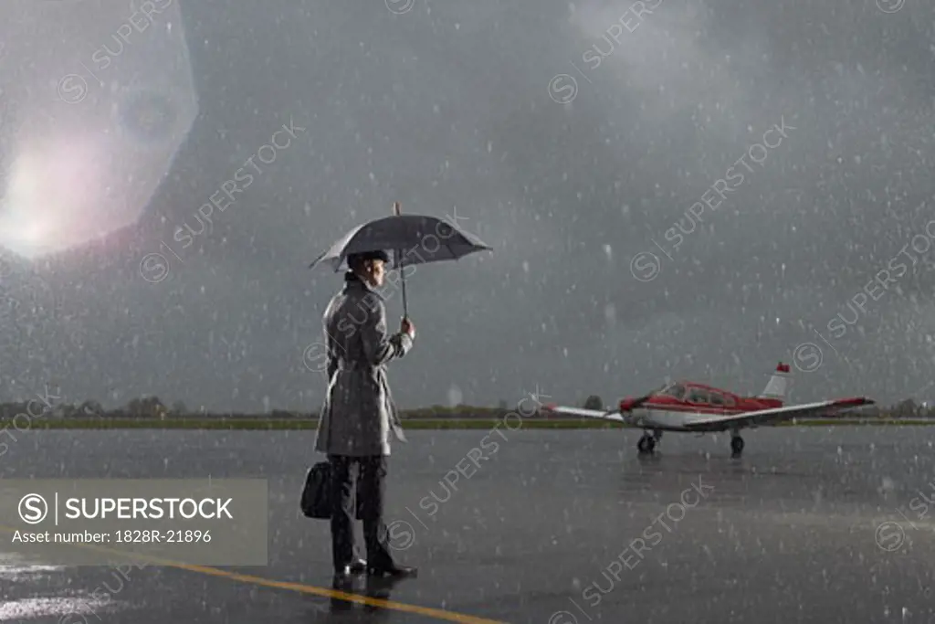 Businessman Standing on Tarmac in Rainy Weather   