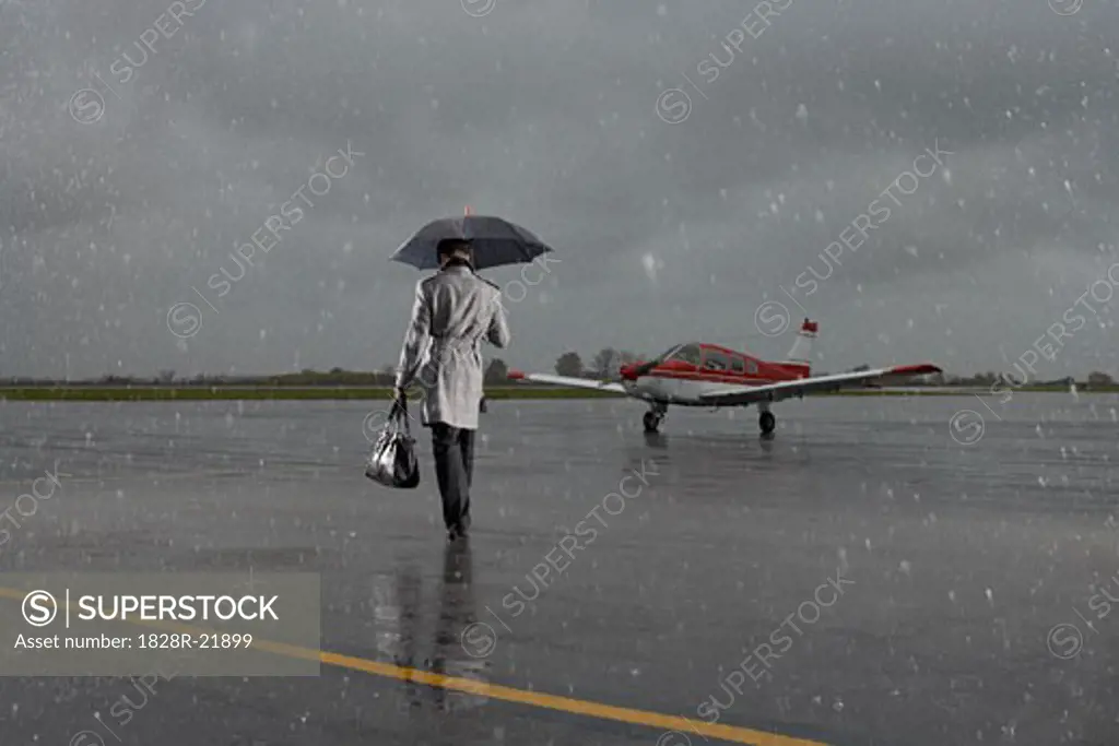 Backview of Businessman Walking on Tarmac in Rainy Weather   