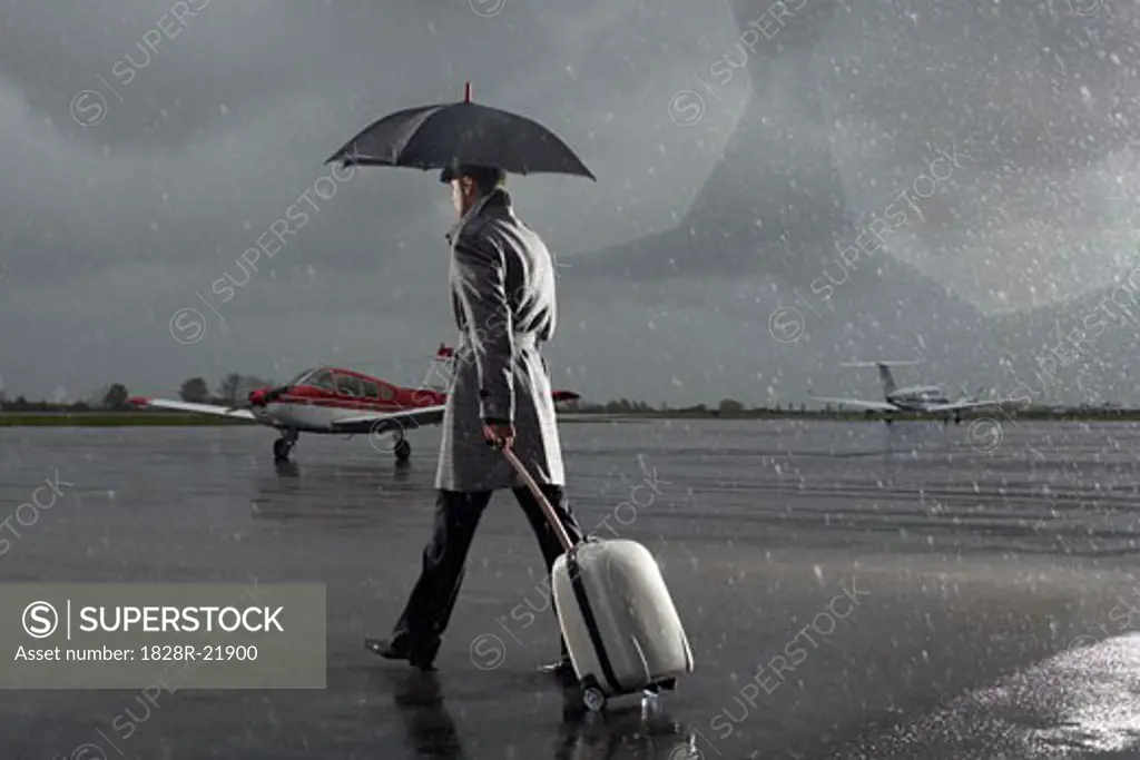 Businessman Walking on Tarmac in Rainy Weather   