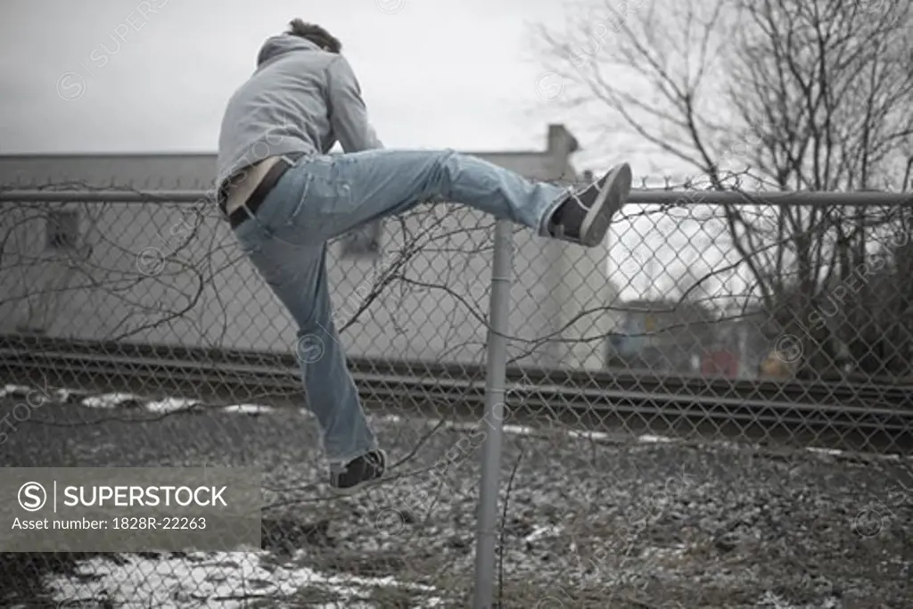 Man Climbing over Fence   