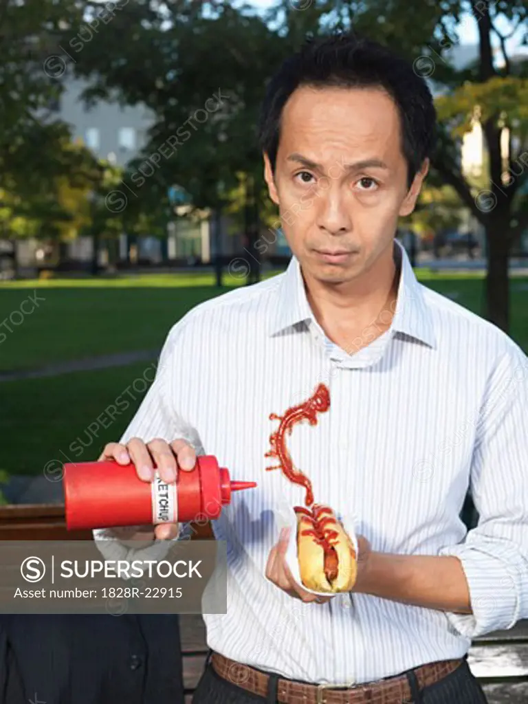 Man with Hot Dog Squirting Ketchup on Shirt   