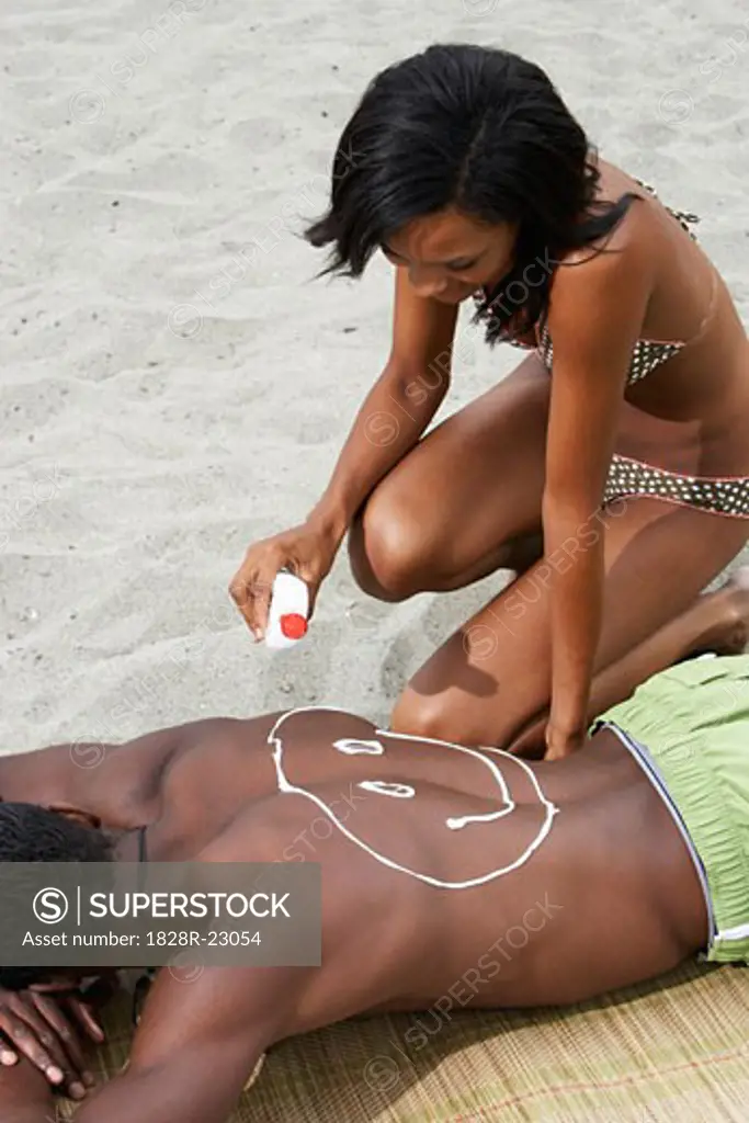Woman Applying Sunscreen on Man's Back   