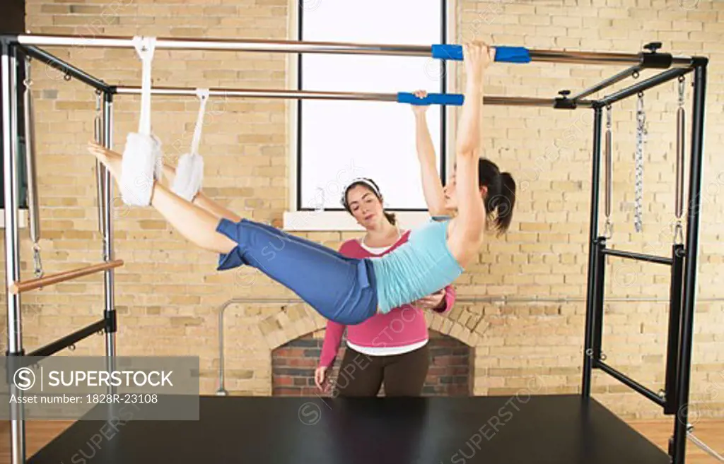 Woman Exercising With Pilates Instructor   