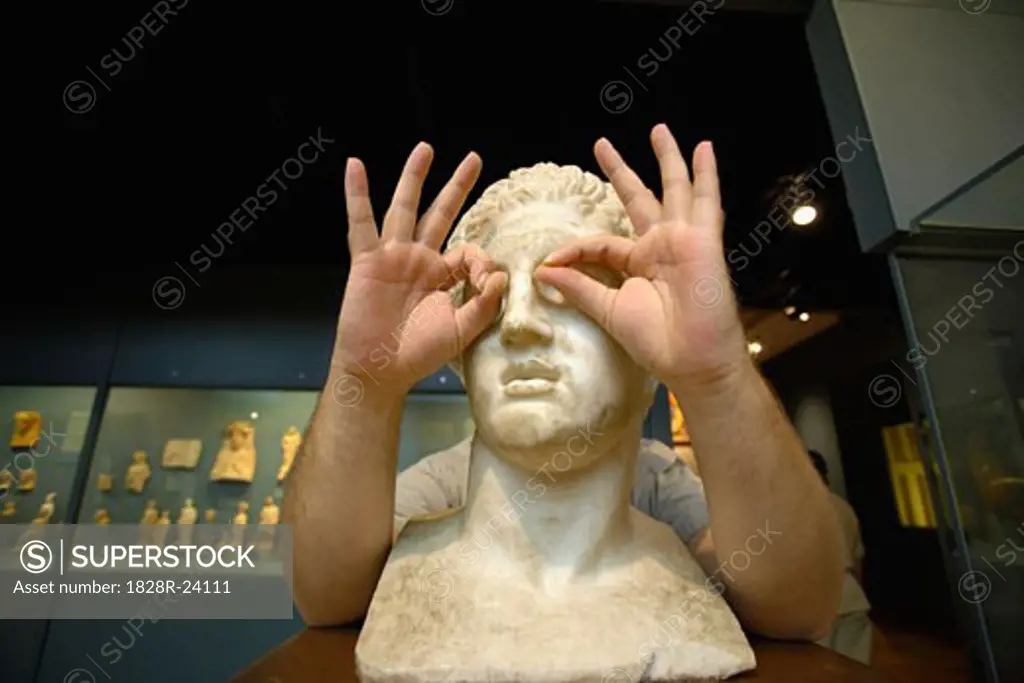 Man Making Glasses with Hands on Statue   
