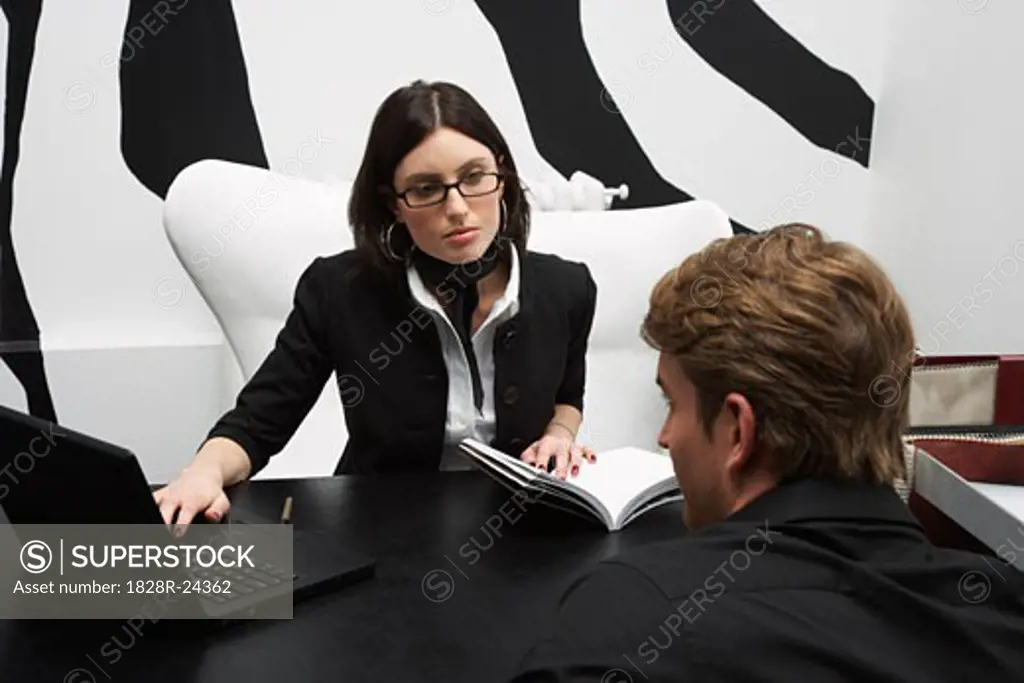 Businesswoman Sitting with Businessman at Desk   