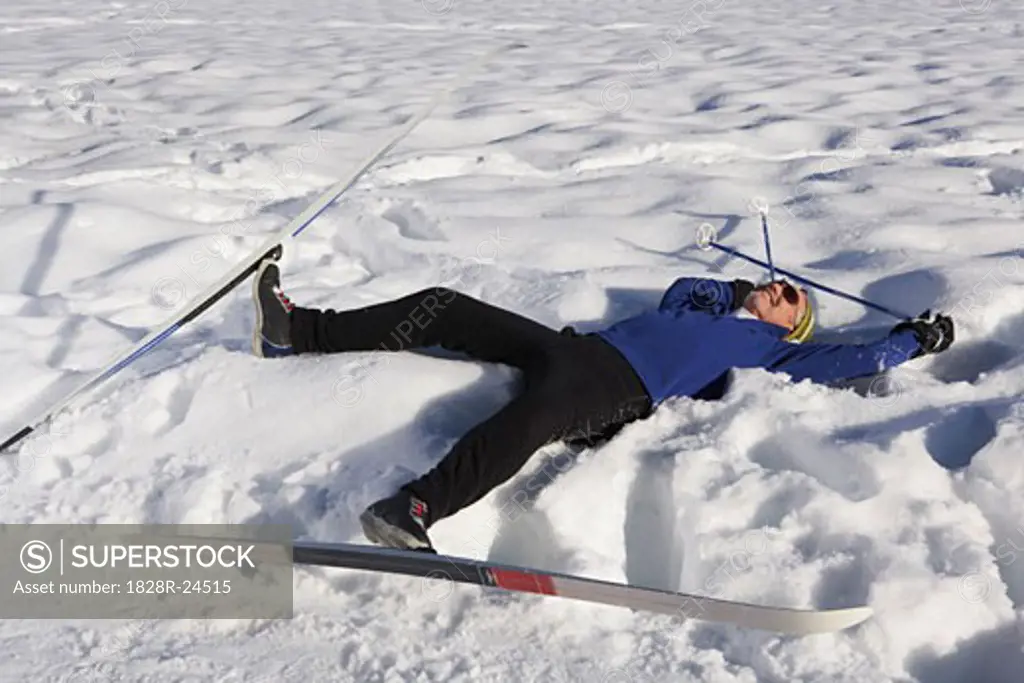 Man Wearing Skis, Lying in Snow   