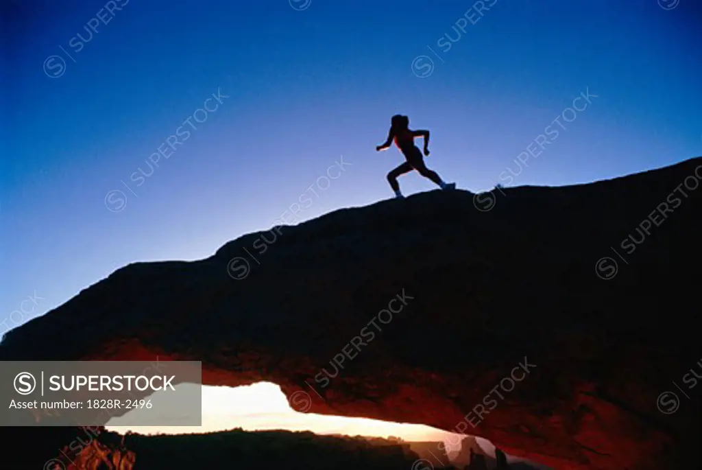 Silhouette of Woman Running on Rock Formation   