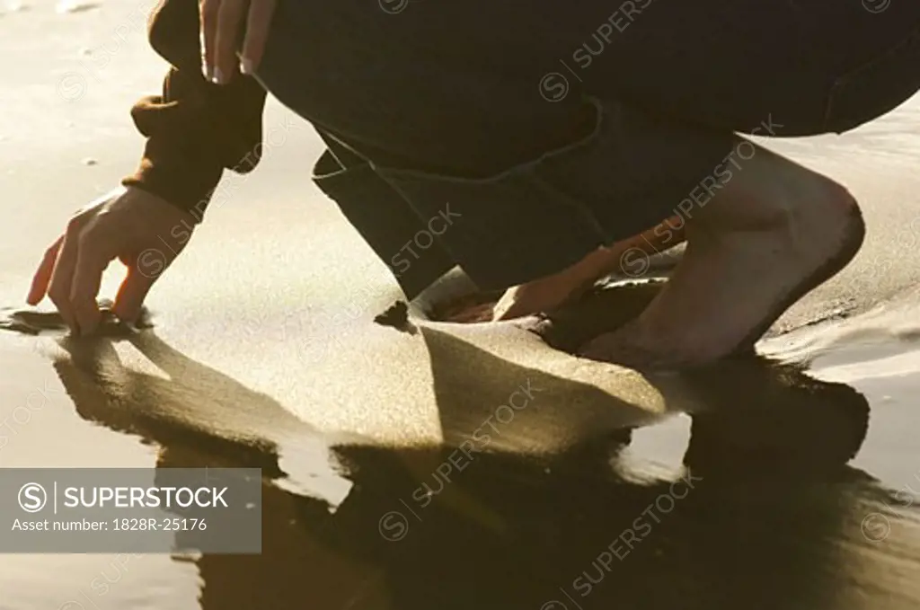 Woman Picking Something out of Sand   