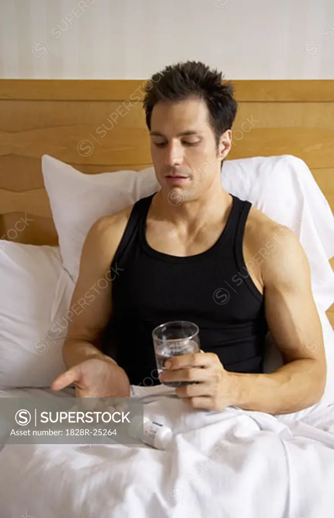 Man in Bed, Taking Pills   