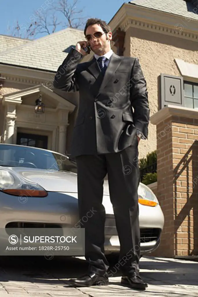 Businessman with Cellular Phone in Driveway   