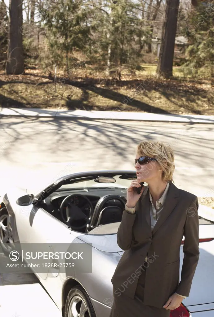Businesswoman with Cellular Phone Leaning against Car   