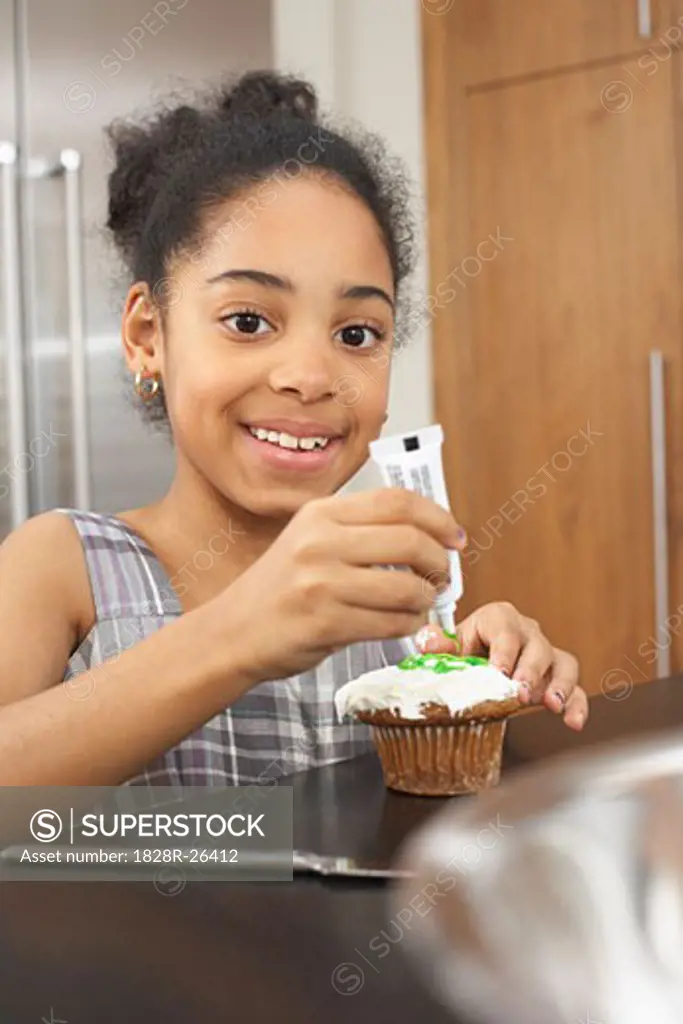 Girl Putting Icing on Cupcake   