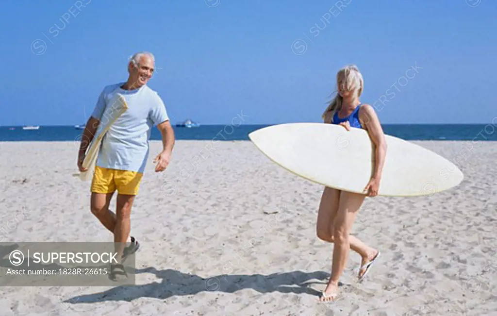 Couple Carring Surfing Boards on Beach   