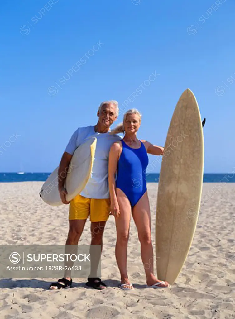 Couple Standing on Beach Holding Surf Boards   