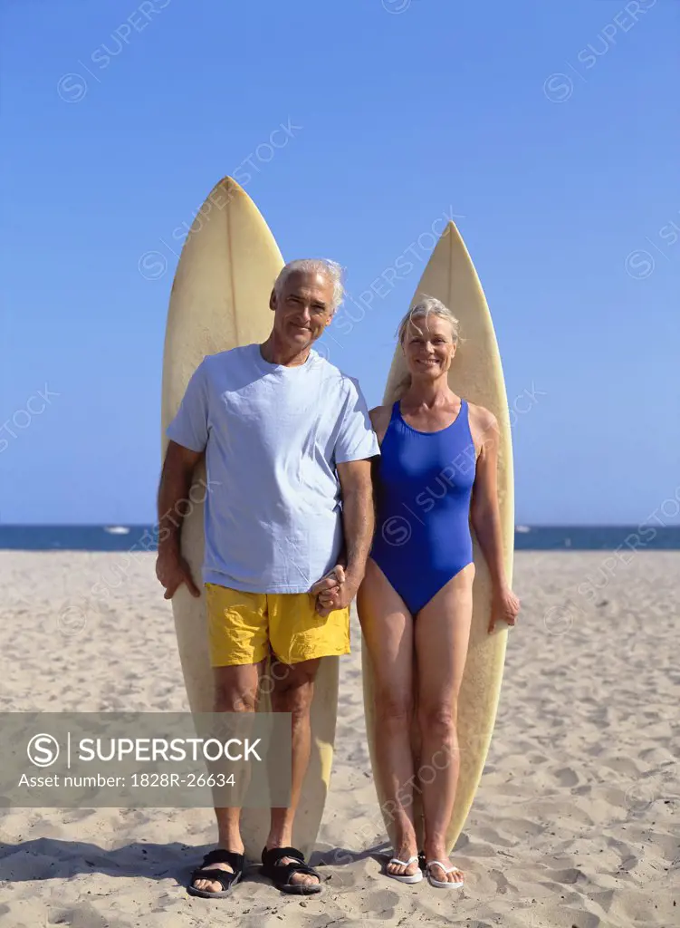 Couple Standing on Beach Holding Surf Boards   