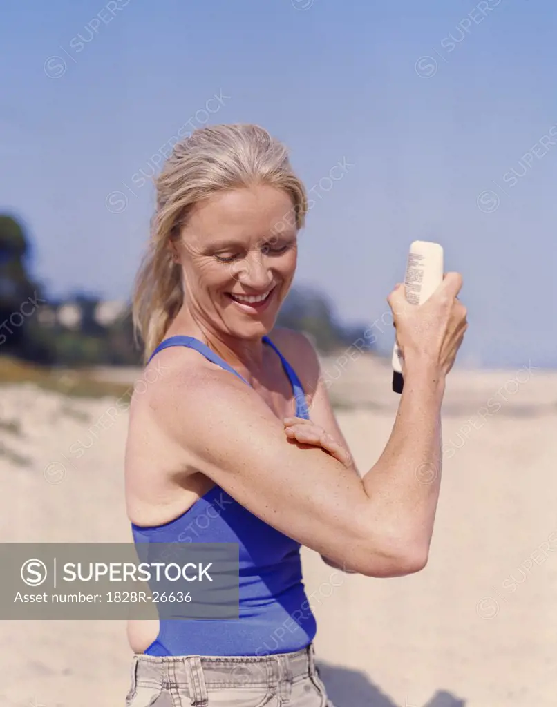 Woman on Beach Applying Sunscreen   