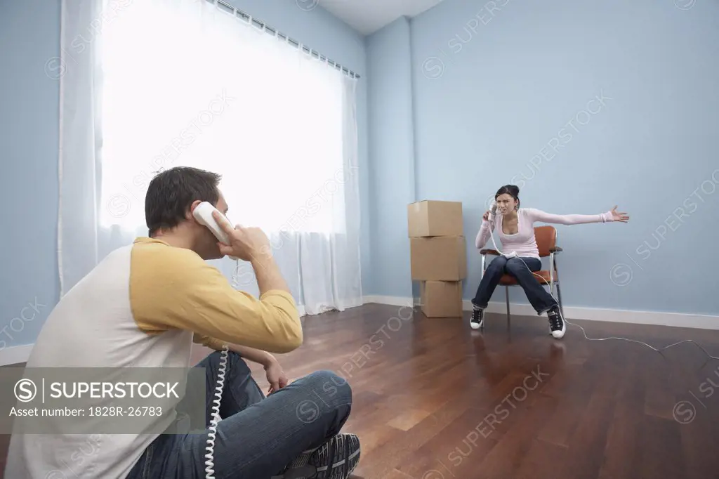 Couple Using Phones in Empty Room   