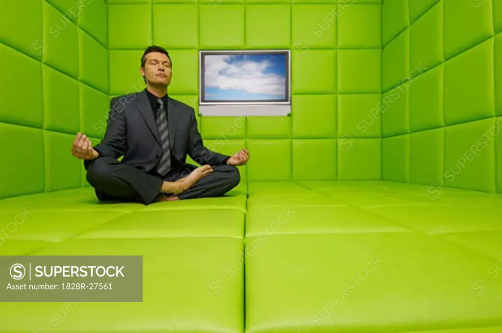 Businessman Meditating in Green Padded Room with Television   