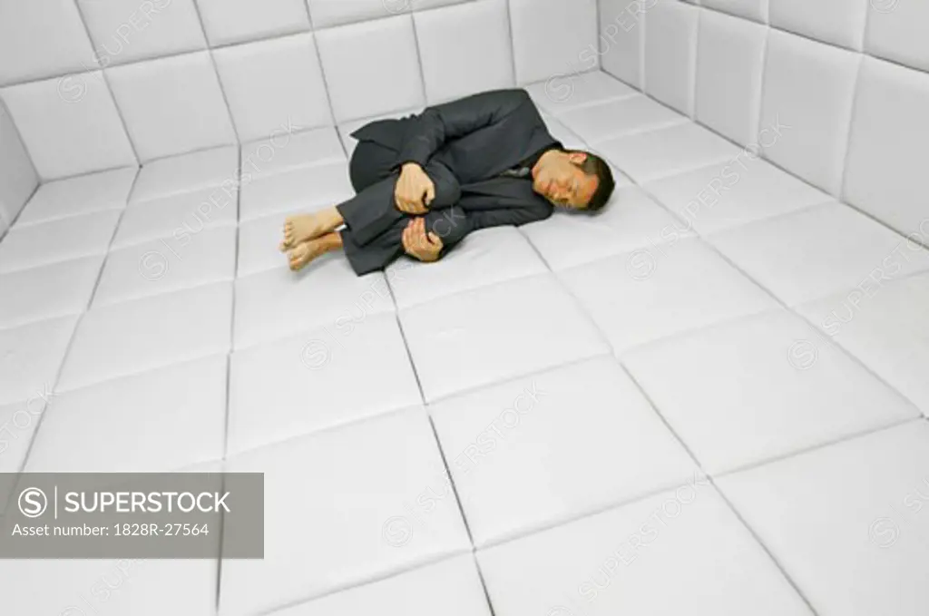 Man in Fetal Position in Padded Room - SuperStock