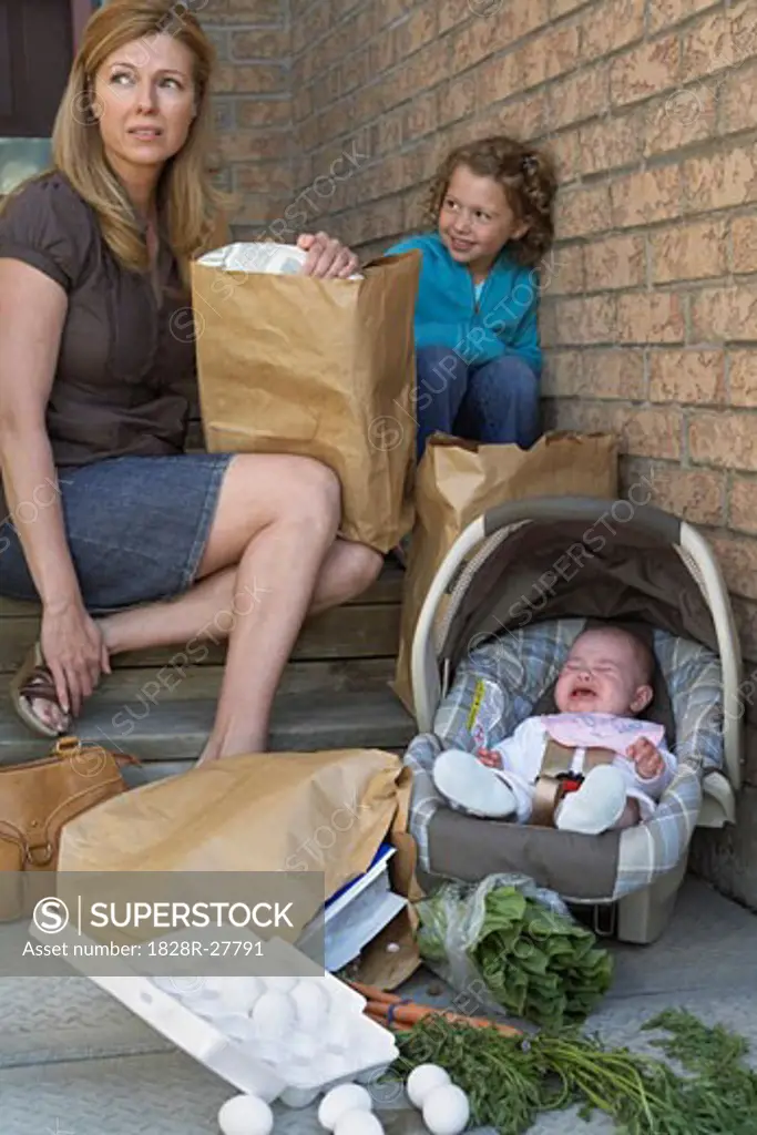 Mother with Children Sitting on Front Steps of House, Carrying Groceries   
