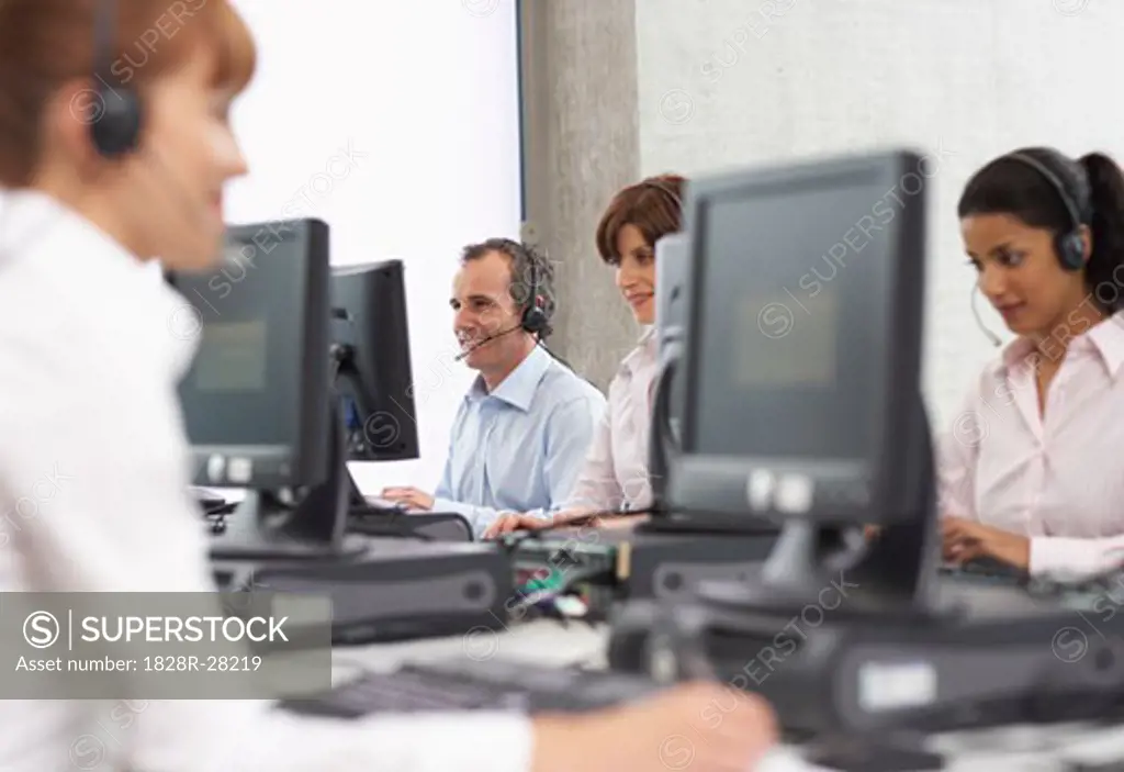Business People Working on Computers with Headsets   