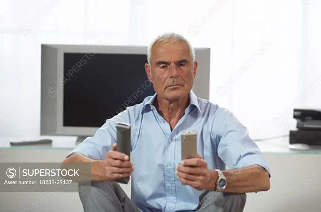 Man Looking at Television Remote Controls   