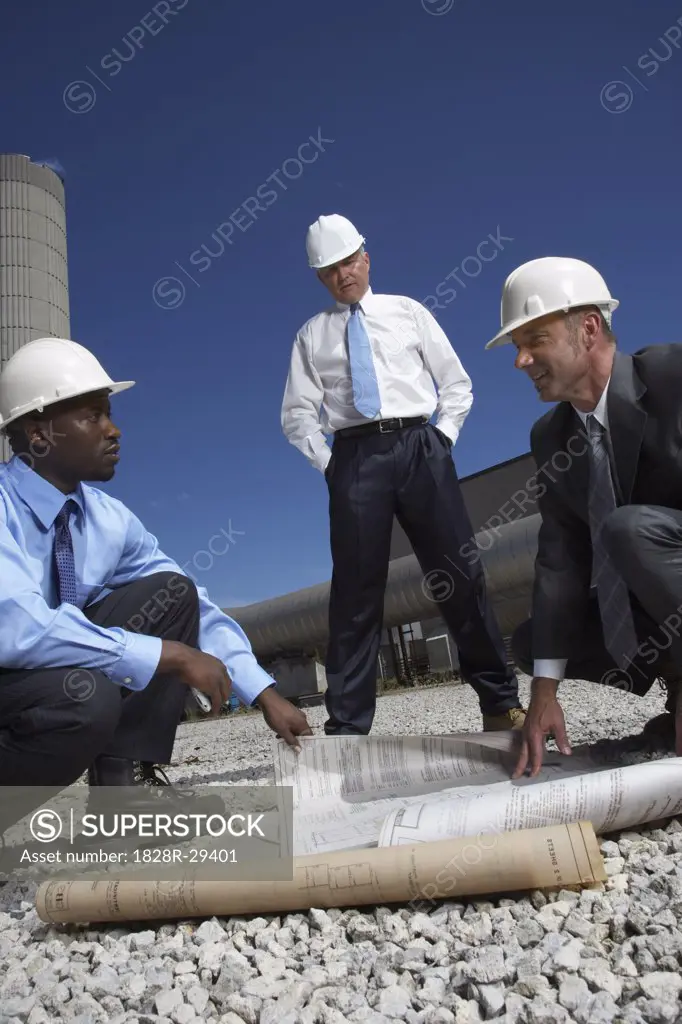 Businessmen Looking at Blueprint Outside of Factory   