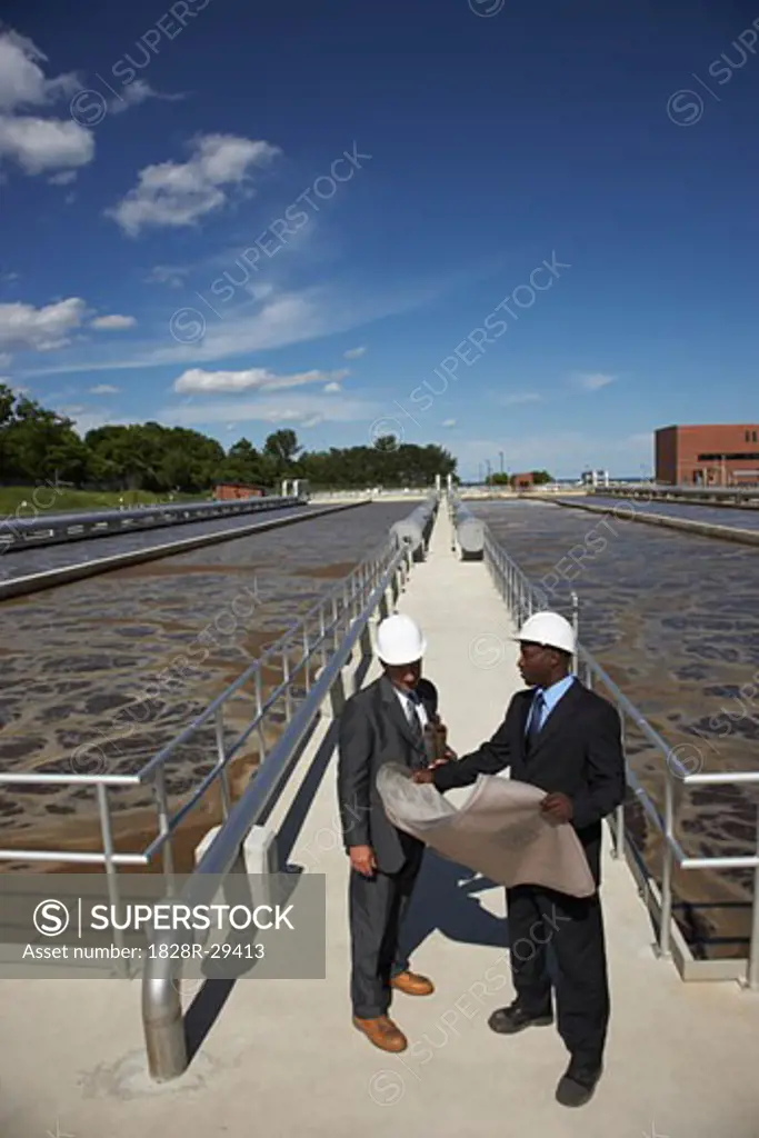 Businessmen Looking at Blueprint Outside Water Treatment Plant   