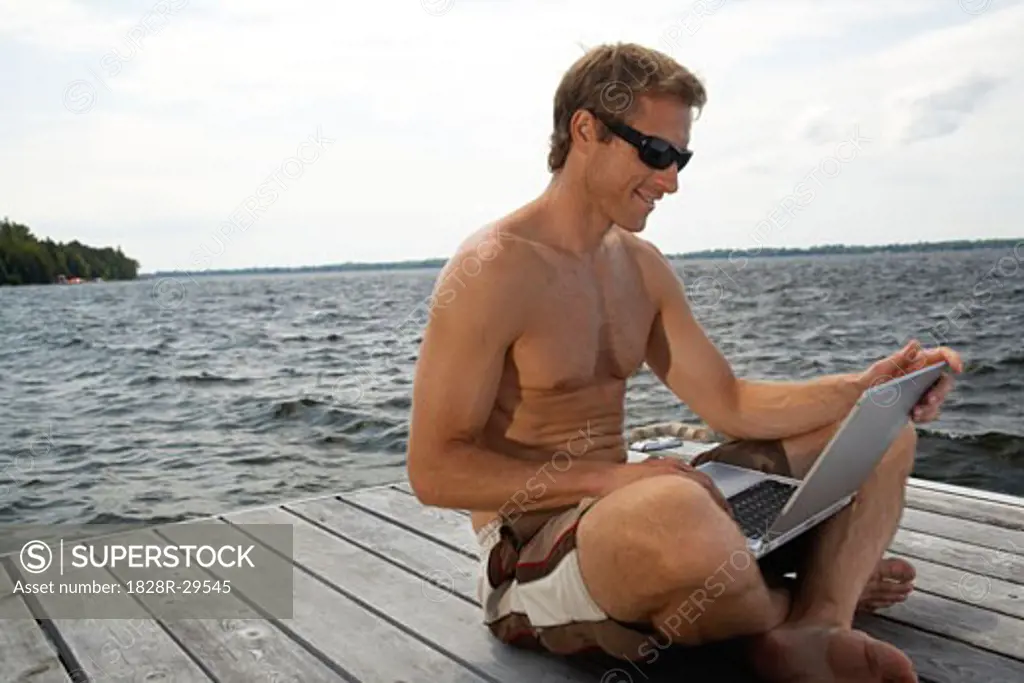 Man Using Laptop Computer on Dock   