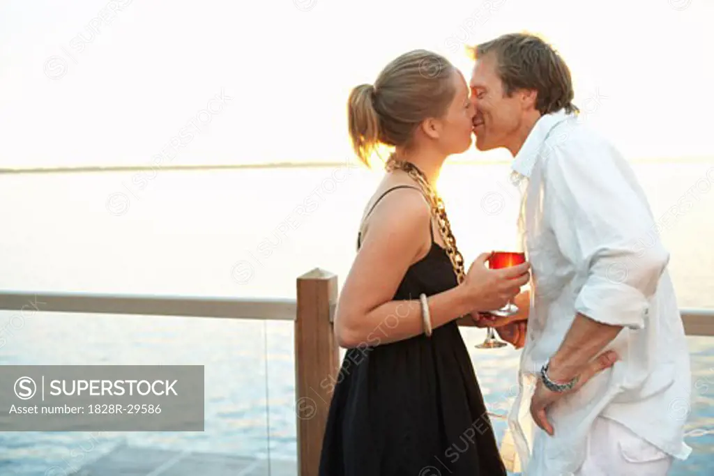 Couple Kissing by the Lake at Sunset   