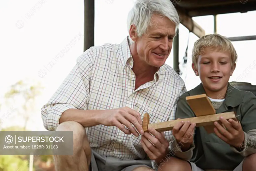 Grandfather and Grandson Playing With Model Airplane   