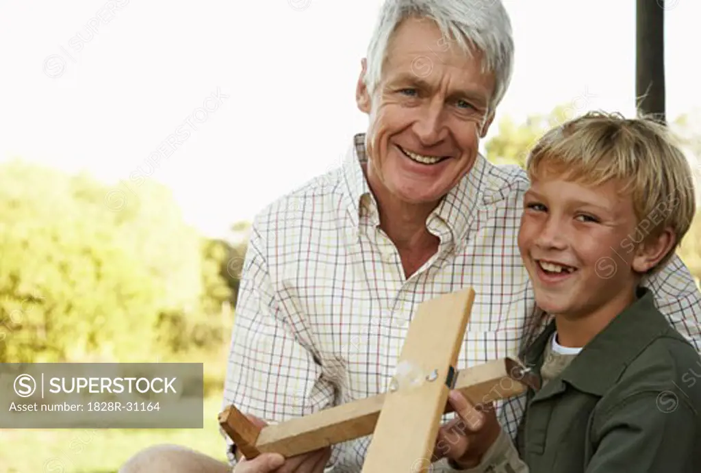 Grandfather and Grandson Playing With Model Airplane   