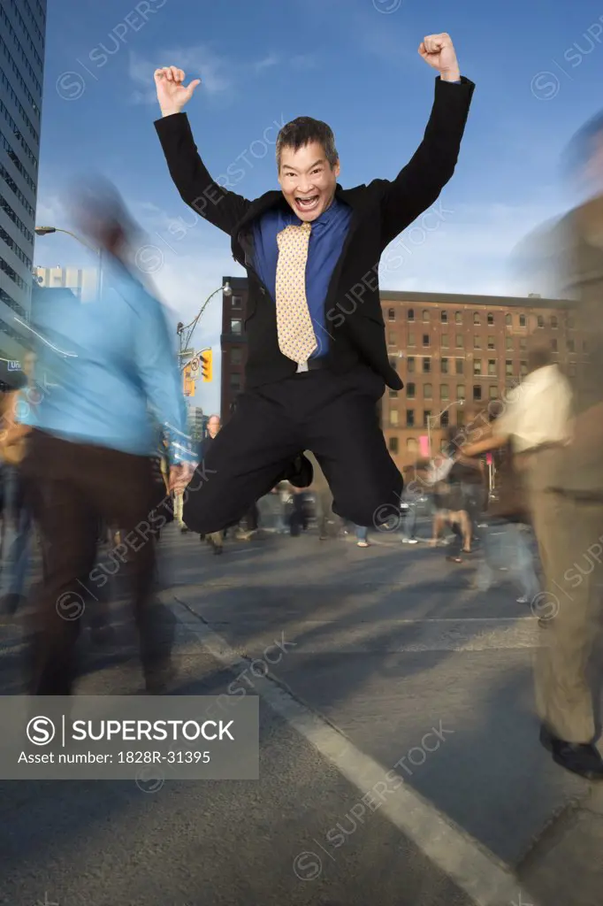 Businessman Jumping for Joy at Downtown Intersection   