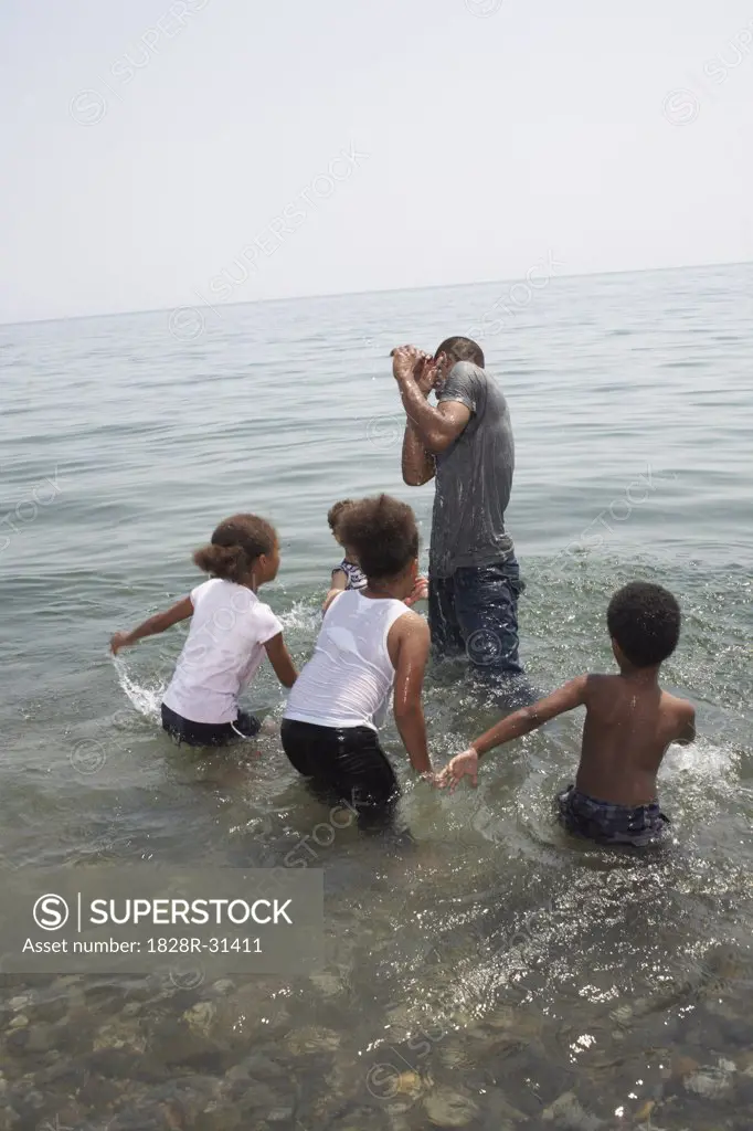 Children Splashing Man in Lake   
