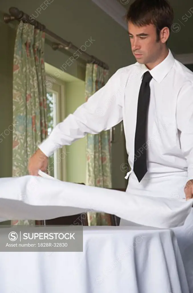Waiter Putting Tablecloth on Table   