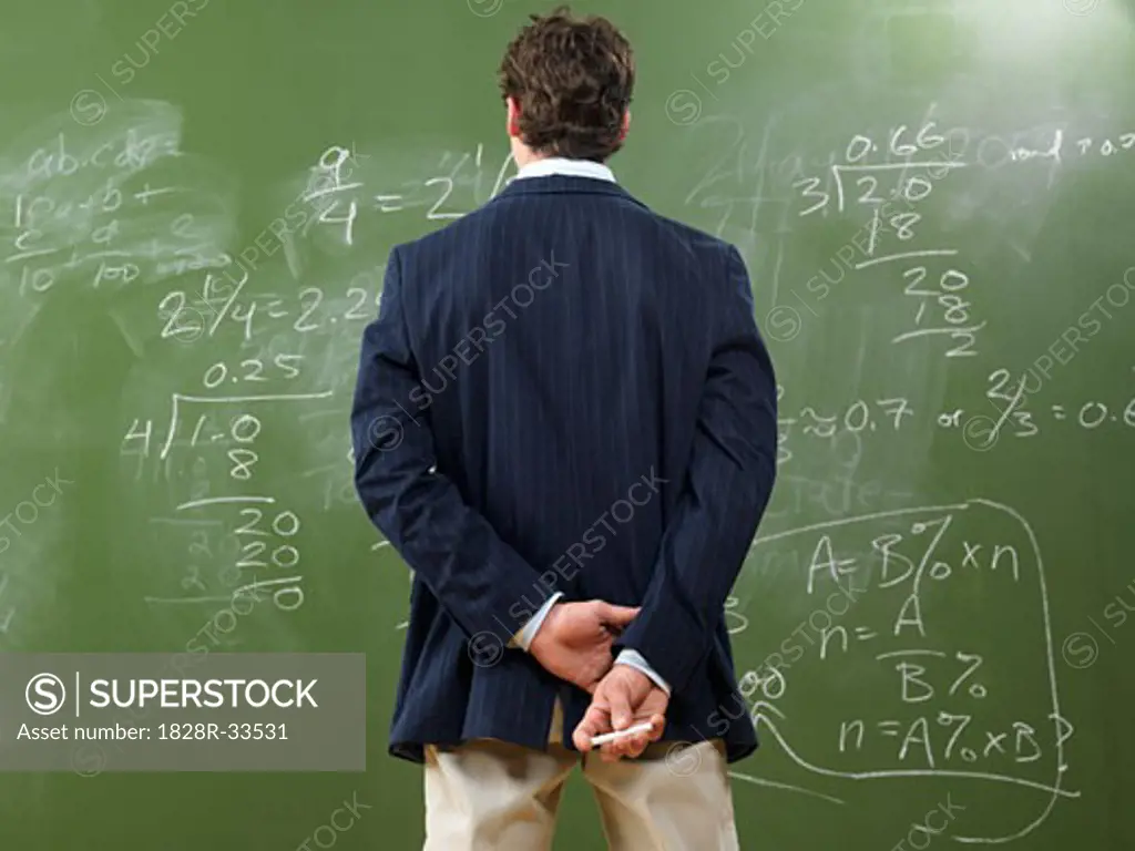 Teacher Looking at Math Problems on Blackboard   